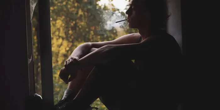 窓辺でタバコを吸う男性