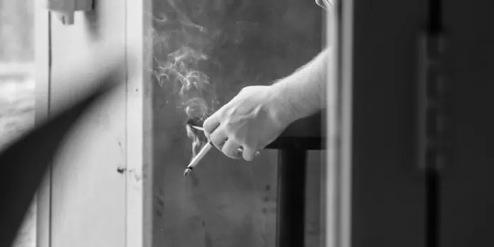 窓辺でタバコを吸う