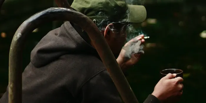 湖畔でタバコを吸う男性