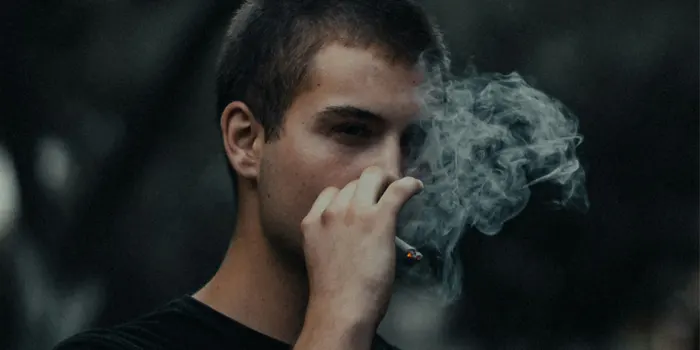 紙巻きタバコの煙を吐く男